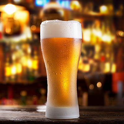 close up of cold glass of beer in a bar on a wooden table